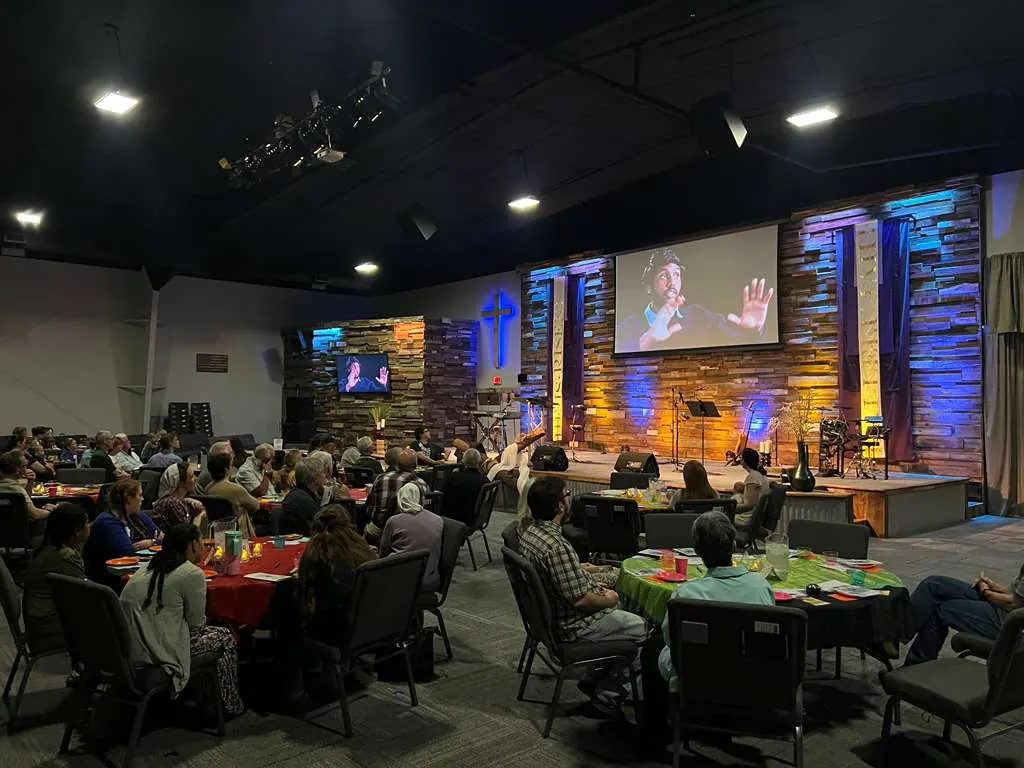 Guests gathered at tables watching the livestream from India