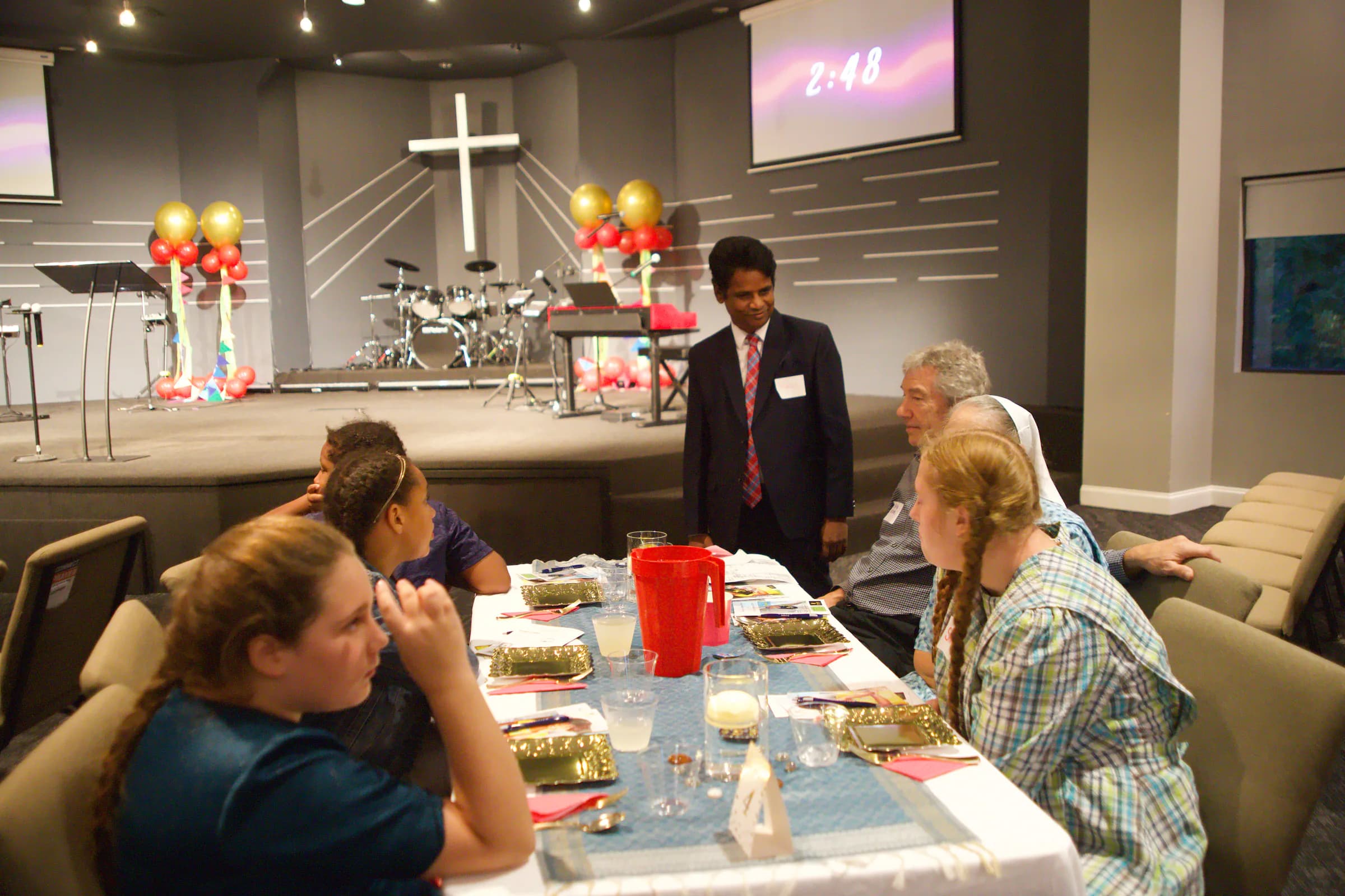 A ministry leader greeting a table of guests in front of the stage