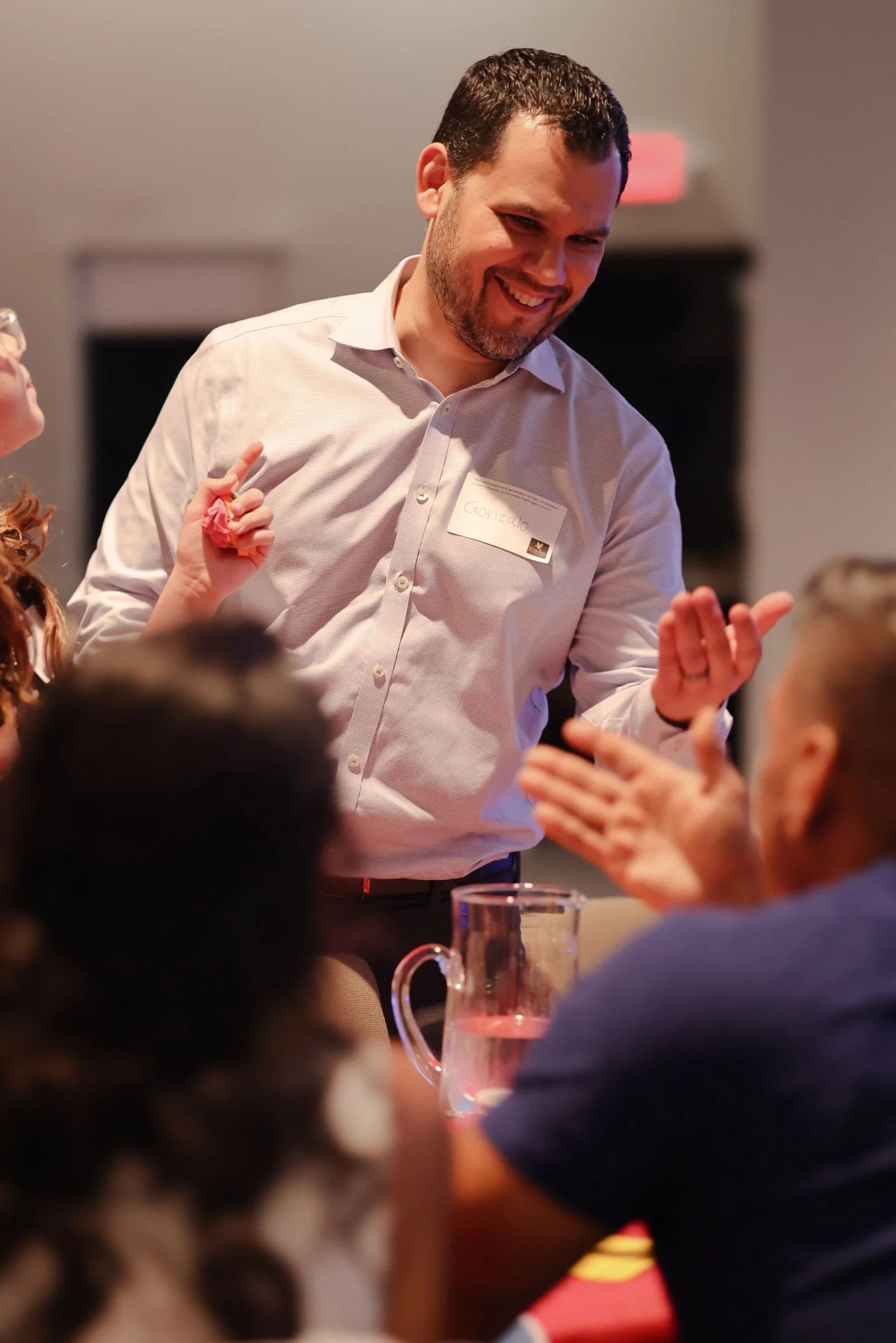 A guest laughing and clapping with friends at his table