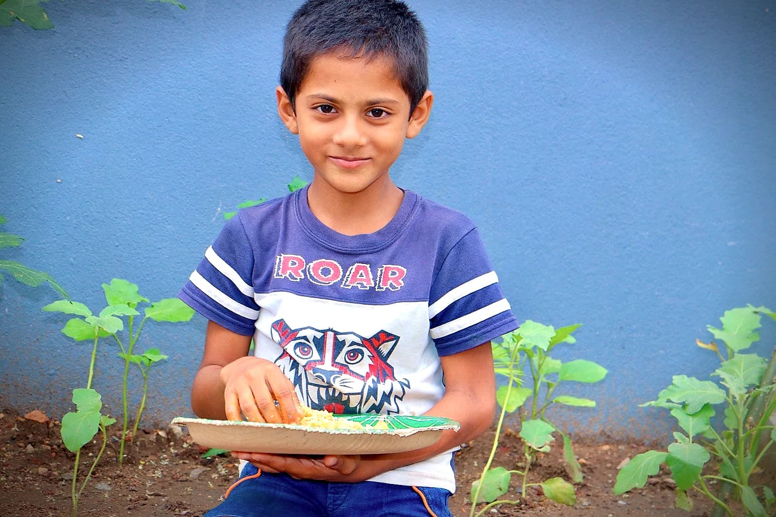 A smiling boy holding a plate of food