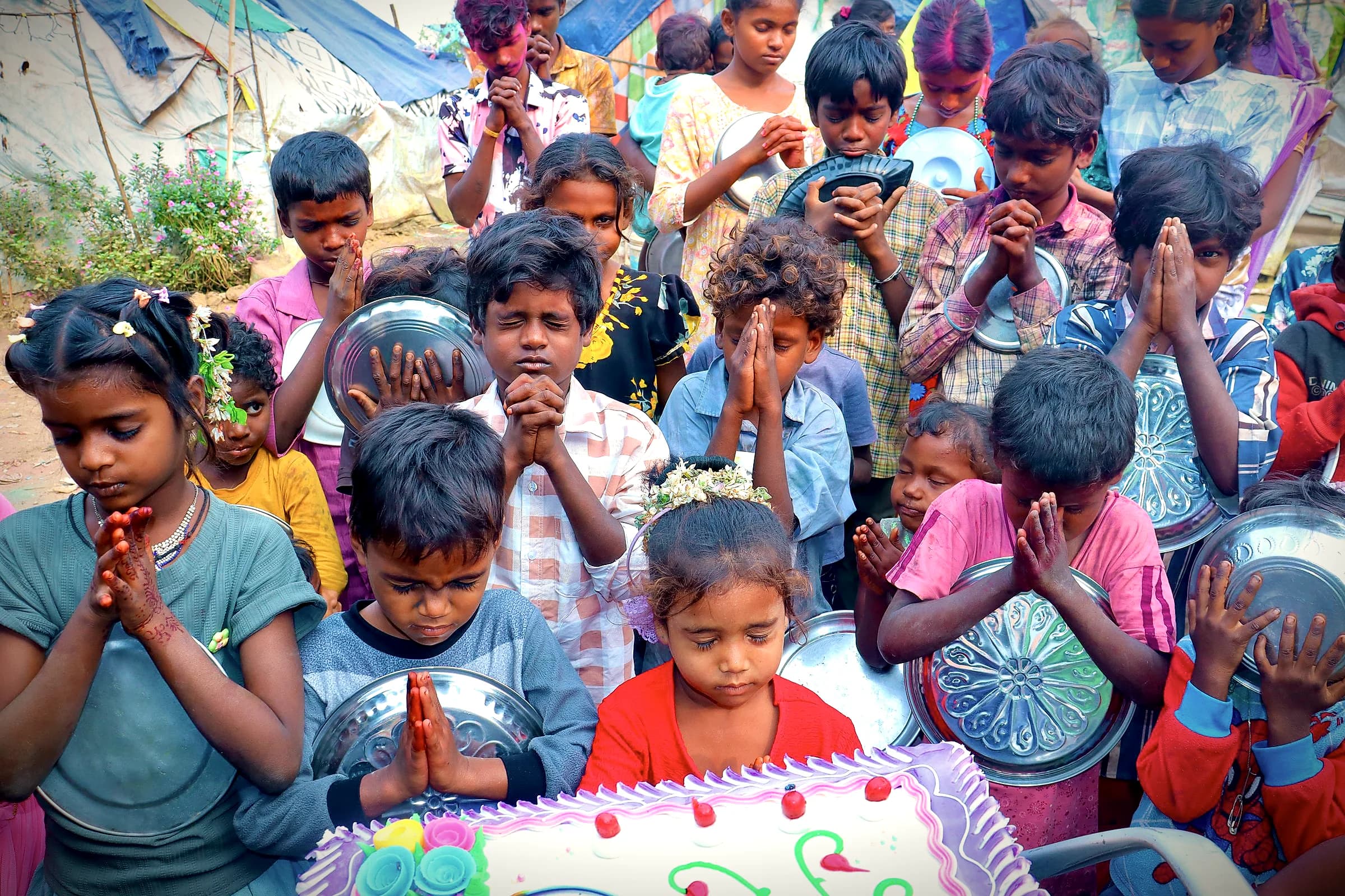 A group of children praying before a shared meal