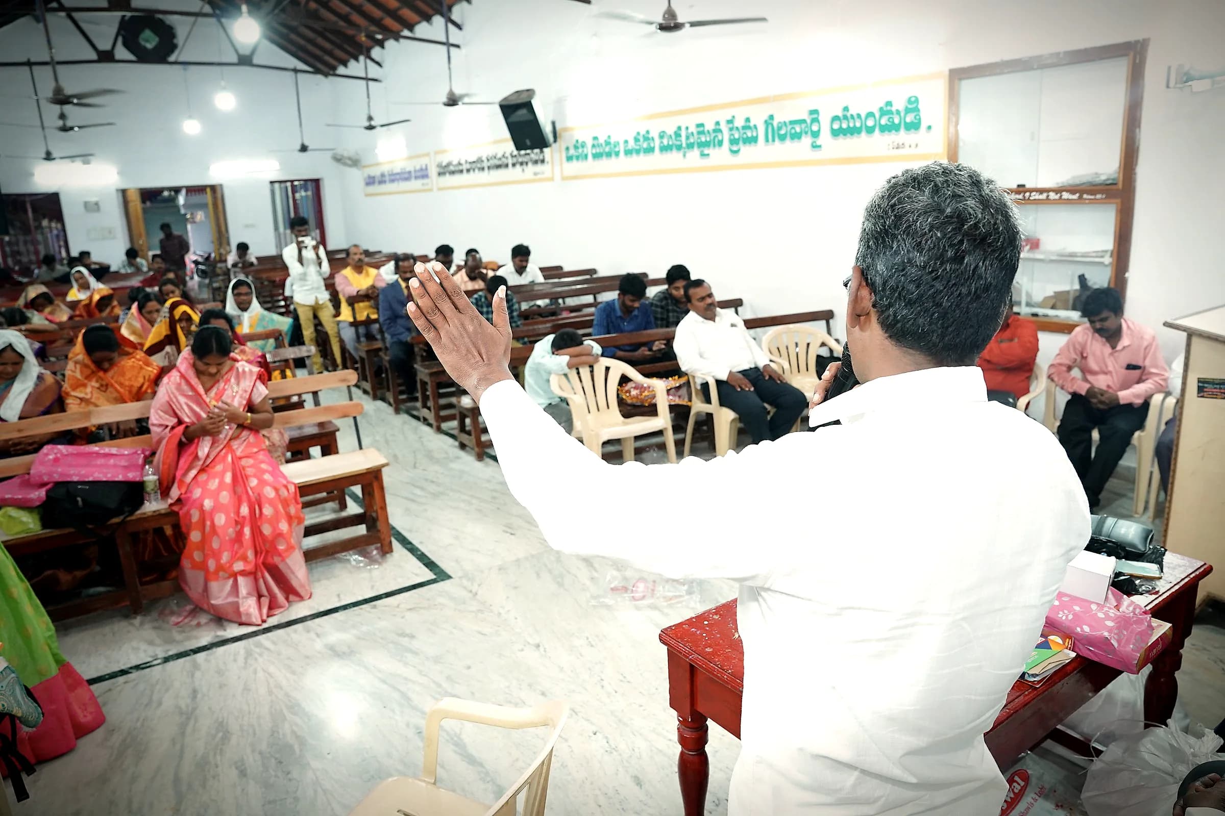 A pastor raising his hand in prayer over a congregation
