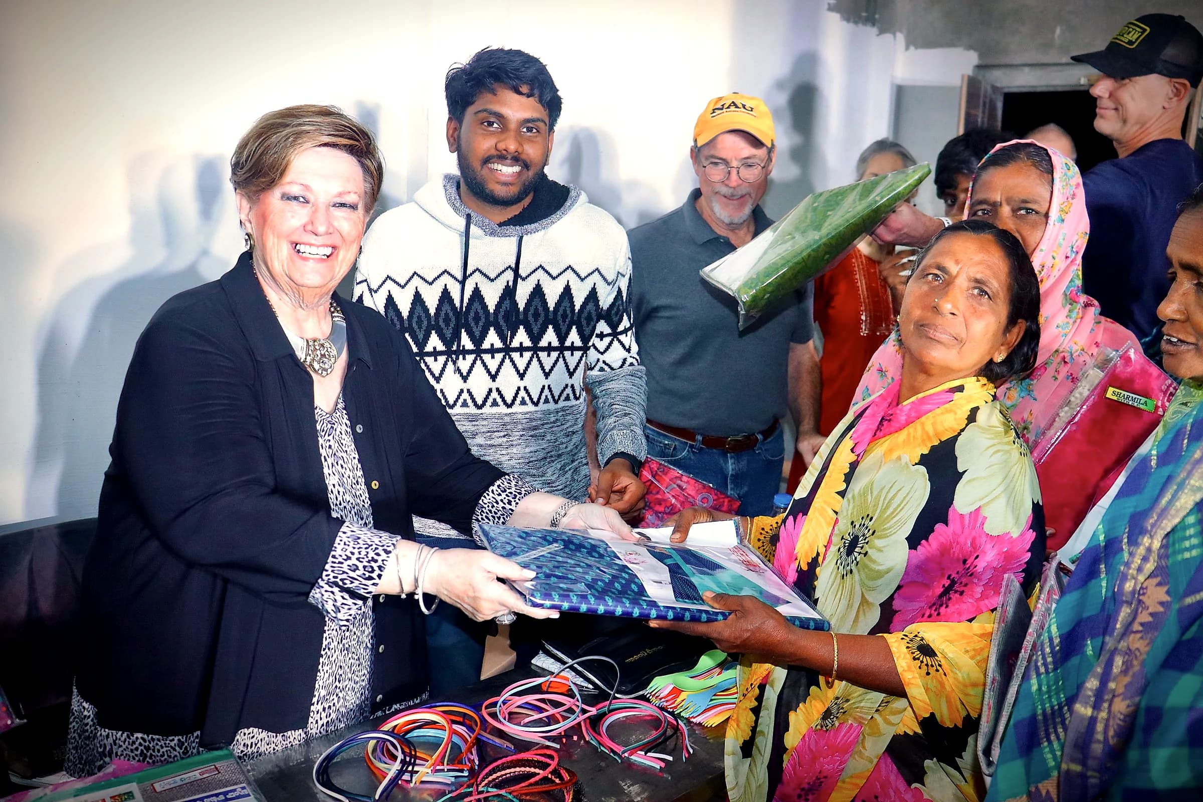 A woman receiving a gift package from a visiting team