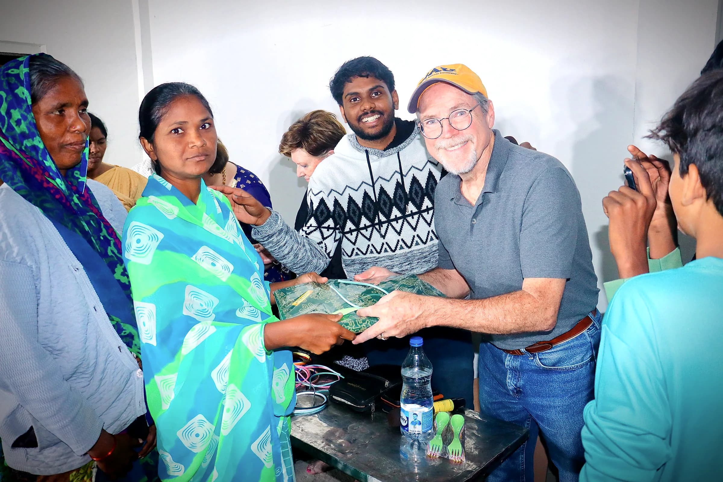 A woman smiling as she receives a sari from team members