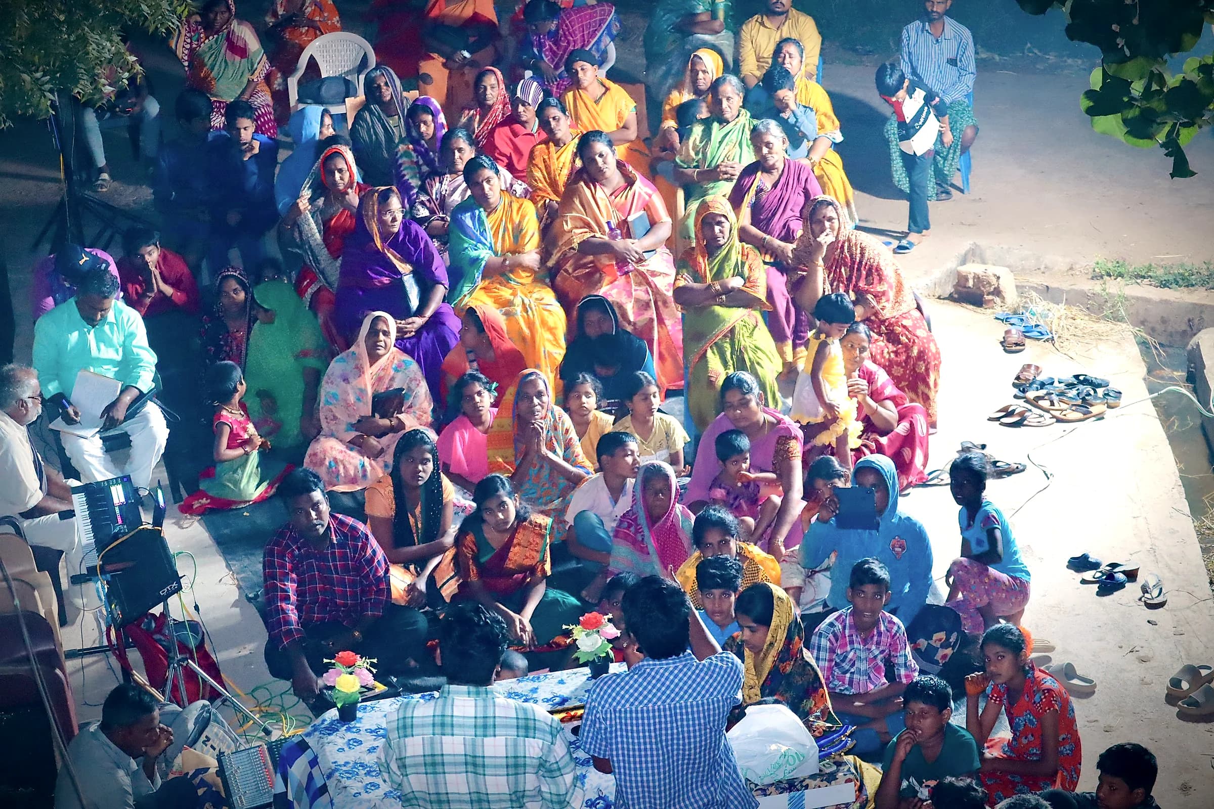 A large gathering of women in colourful saris seen from above