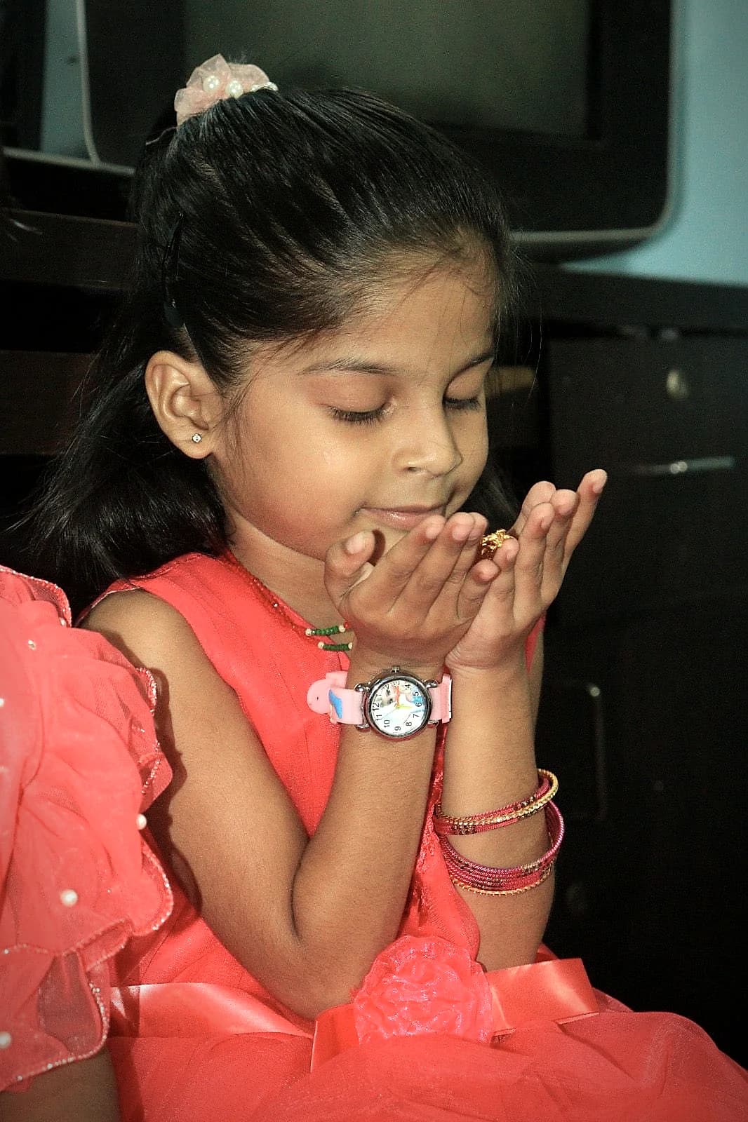 A girl in a red dress praying with cupped hands