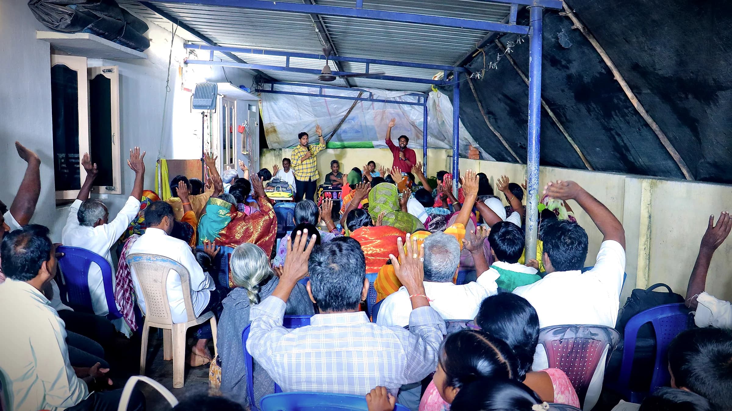 Believers with raised hands under a covered courtyard