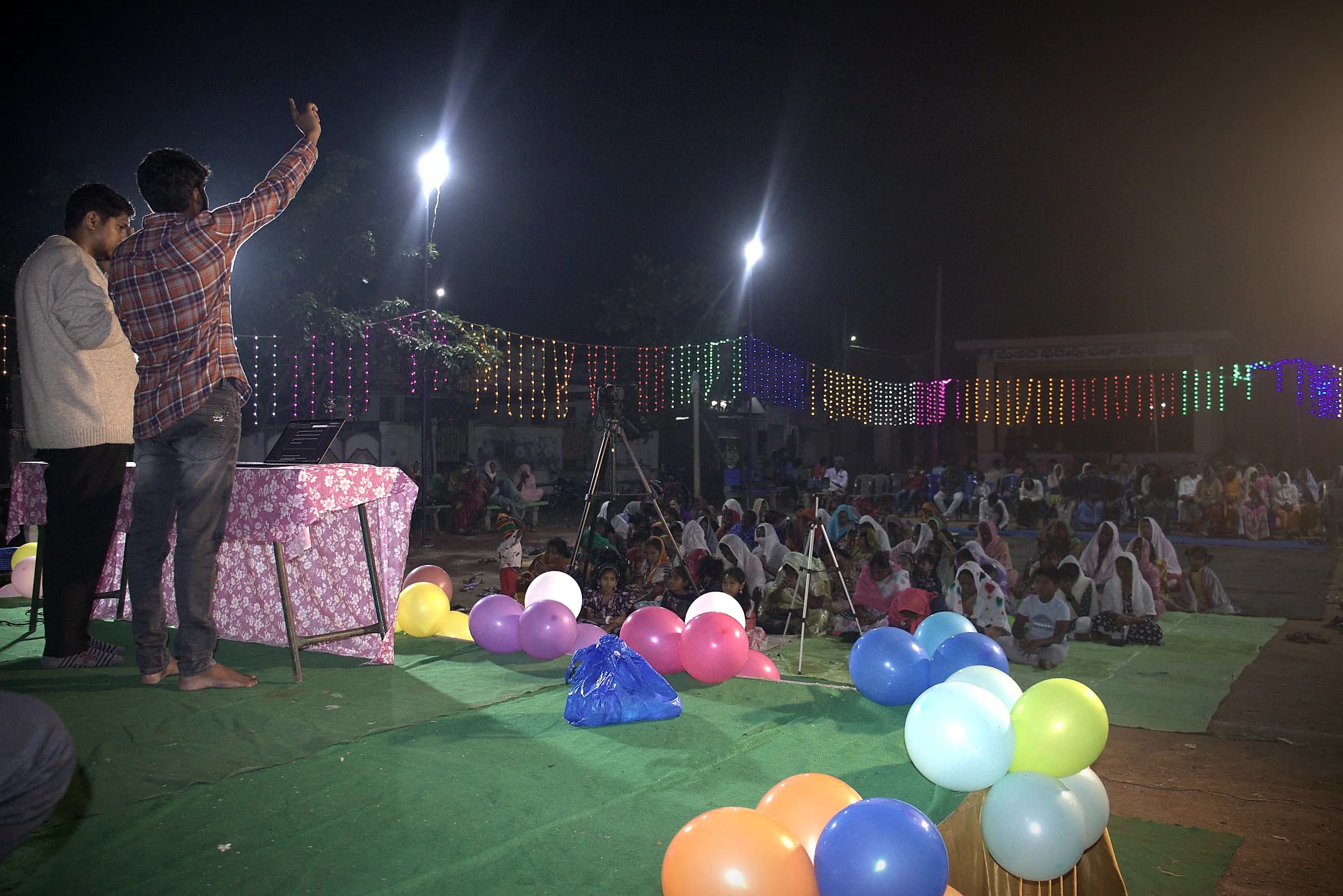 A preacher on stage at a night crusade with balloons along the front