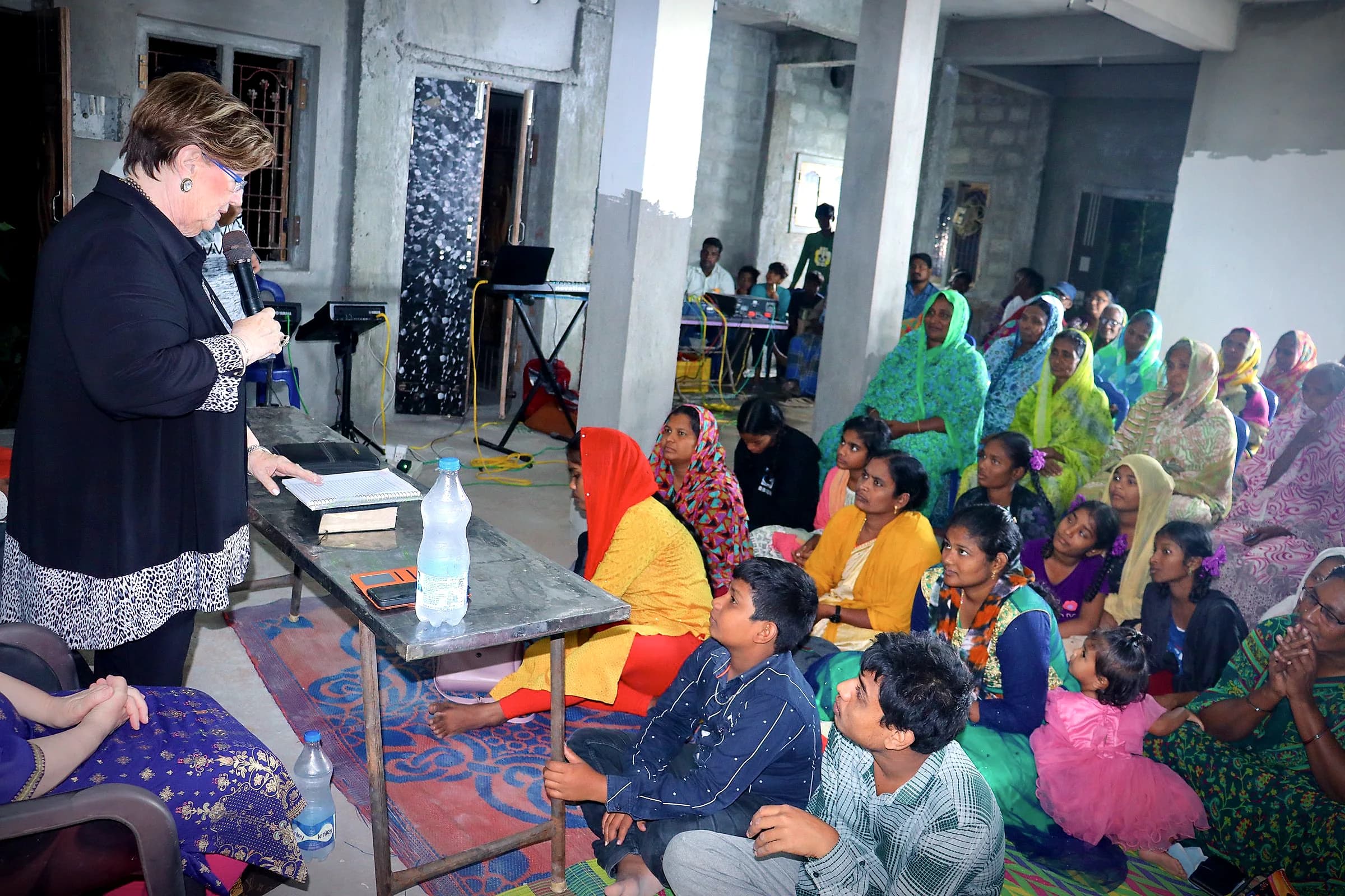 A speaker addressing women seated in a courtyard